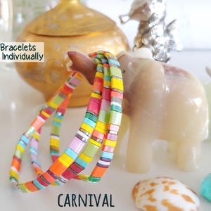 Peut inclure: Un ensemble de bracelets Tila compos&eacute; de perles carr&eacute;es multicolores dans des tons orange, jaune, rose, bleu et vert. Le texte "Tila Bracelets Sold Individually" et "CARNIVAL" est imprim&eacute; sur l'image.