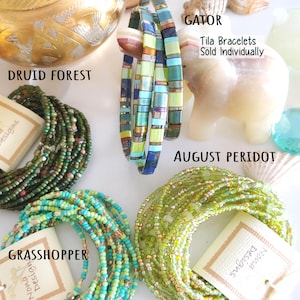 Peut inclure: Une collection de bracelets en perles comprenant les styles Druid Forest, Gator, August Peridot et Grasshopper. L'image pr&eacute;sente des bracelets Tila vendus individuellement, avec diverses perles de rocaille vertes, bleues et m&eacute;talliques.