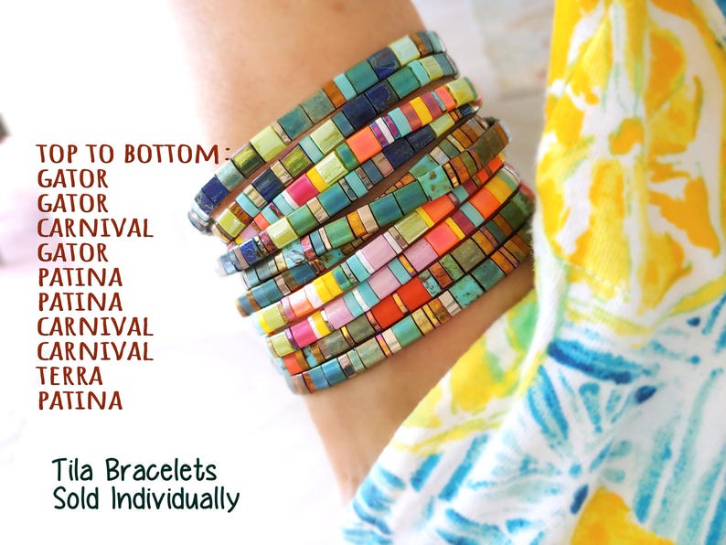 Peut inclure: Une pile de dix bracelets Tila compos&eacute;s de perles carr&eacute;es aux couleurs vari&eacute;es, notamment bleu sarcelle, orange, jaune, rose et des tons m&eacute;talliques. Le texte indique : TOP TO BOTTOM: GATOR, GATOR, CARNIVAL, GATOR, PATINA, PATINA, CARNIVAL, CARNIVAL, TERRA, PATINA. Tila Bracelets Sold Individually.