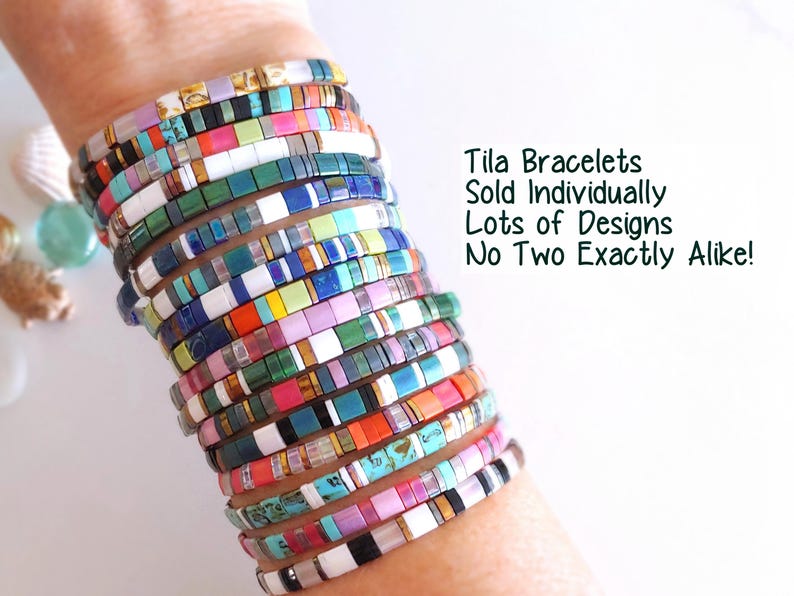 Peut inclure: Une pile de bracelets de perles Tila multicolores pr&eacute;sentant divers motifs et teintes, notamment rose, bleu, vert, blanc et des tons m&eacute;talliques. Le texte indique : Tila Bracelets Sold Individually Lots of Designs No Two Exactly Alike!