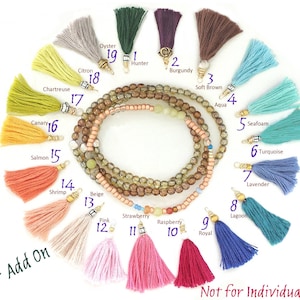 May include: A selection of 19 colourful tassel charms numbered 1 to 19. The tassels are arranged in a circle around a beaded bracelet. The bracelet is made of brown, beige, and green beads. The tassels are made of various colours, including red, pink, orange, yellow, green, blue, purple, and brown. The tassels are all approximately 5 cm long. Not for individual sale.