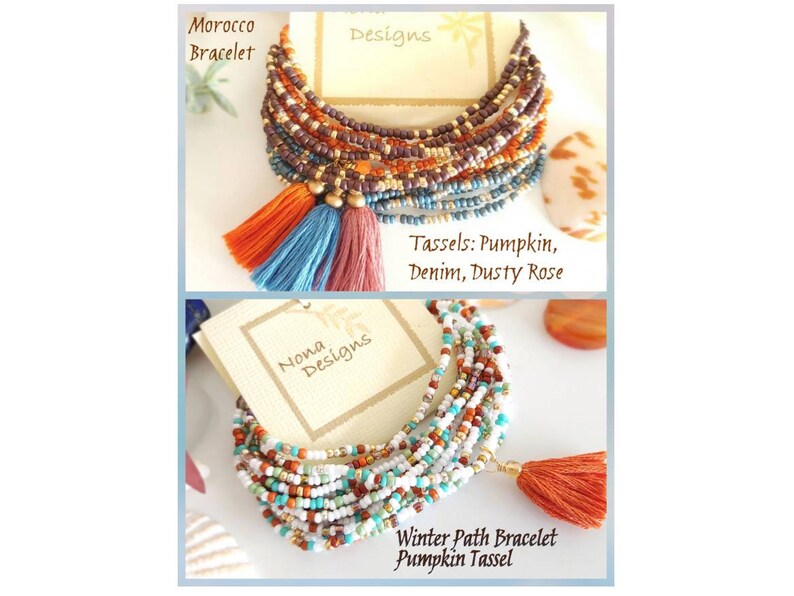 May include: Two multi-strand beaded bracelets with tassels. The top bracelet is brown, orange, and blue with three tassels. The bottom bracelet is white, orange, and turquoise with one tassel. The bracelets are labeled "Morocco Bracelet" and "Winter Path Bracelet Pumpkin Tassel".