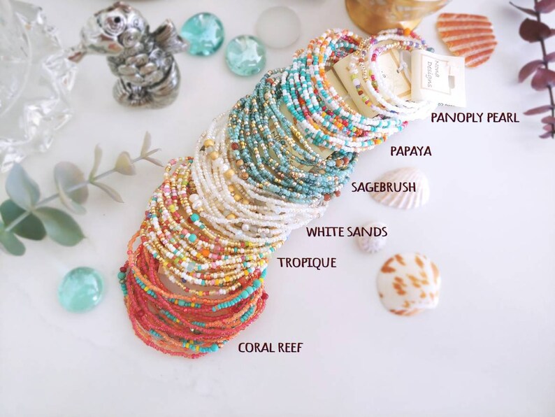 K&ouml;nnte beinhalten: Ein Stapel bunter Perlenarmb&auml;nder mit Namen wie "Coral Reef", "Tropique", "White Sands", "Sagebrush", "Papaya" und "Panoply Pearl".