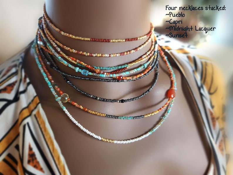 May include: Four beaded necklaces in different colours, layered together. The necklaces are labelled Pueblo, Capri, Midnight Lacquer, and Sunset. The image includes the text: "Four necklaces stacked: ~Pueblo ~Capri ~Midnight Lacquer ~Sunset."
