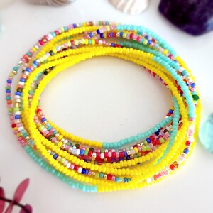 K&ouml;nnte beinhalten: Ein mehrfarbiges Perlenarmband mit gelber Mitte und t&uuml;rkisfarbenen Akzenten.