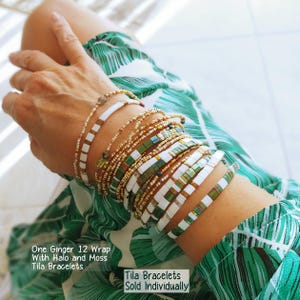 Peut inclure: Une collection de bracelets Tila avec des carreaux carr&eacute;s blancs, vert mousse et or m&eacute;tallique, ainsi que des brins de perles d&eacute;licats. Le texte indique : One Ginger 12 Wrap With Halo and Moss Tila Bracelets. Tila Bracelets Sold Individually.