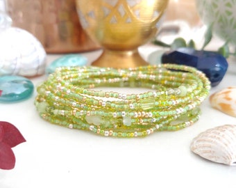 Puede incluir: Una pulsera de múltiples hilos de cuentas que combina pequeñas cuentas de vidrio verde lima translúcido, espaciadores metálicos de tono plateado y fragmentos de piedra verde pálido dispuestos en un patrón circular continuo.