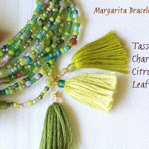 May include: A multi-strand beaded bracelet with green, blue, and white beads. The bracelet has three tassels attached to it, in the colors chartreuse, citron, and leaf. The text "Margarita Bracelet" and "Tassels: Chartreuse Citron Leaf" is visible in the image.