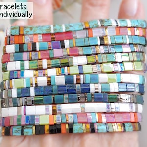 Peut inclure: Une collection de bracelets Tila vendus individuellement, compos&eacute;s de perles carr&eacute;es aux motifs vari&eacute;s incluant turquoise, sunset, slate, rosebud, moss, marine, madras, lapis, lacquer, halo, festival et bengal. Le texte indique Tila Bracelets Sold Individually.