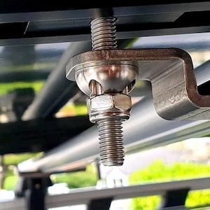 以下が含まれることがあります： ボールジョイントとねじ付きボルトが付いた銀色の金属製取り付けブラケットのクローズアップ。ブラケットは黒い金属棒に取り付けられています。