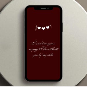 以下が含まれることがあります： スマートフォンは、3つの白いハートのガーランドが付いた、濃い赤色の背景を表示しています。「I can't imagine saying I do without you by my side」というテキストが筆記体で書かれています。
