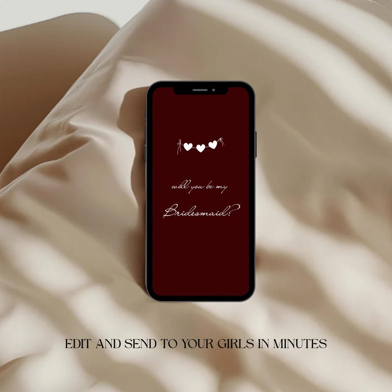 以下が含まれることがあります： バーガンディ色の画面のスマートフォンには、白いスクリプトで「will you be my Bridesmaid?」というテキストが表示され、その上に3つの白いハートがあります。 電話はニュートラルなクリーム色の背景に設定されています。 画像の下部には「EDIT AND SEND TO YOUR GIRLS IN MINUTES」と書かれています。