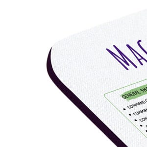 May include: A white mousepad with a black border. The text "MACO" is written in purple at the top of the mousepad. Below the text, a list of "GENERAL SHORTCUTS" is written in green. The list includes keyboard shortcuts for a Mac computer.