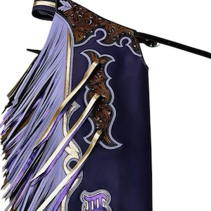 May include: Purple and gold embroidered leather chaps with fringe. The chaps have a decorative design and a purple and gold fringe.