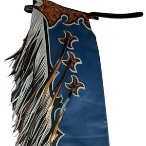 May include: Blue leather chaps with white and brown fringe, featuring a decorative design with gold and green accents.