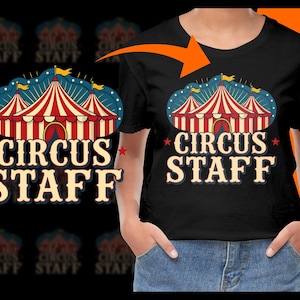 以下が含まれることがあります： 赤と白のストライプのサーカスのテントのデザインと、ヴィンテージフォントで「CIRCUS STAFF」というテキストが特徴の黒いTシャツ。デザインには星と旗が含まれています。