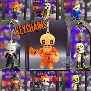 May include: Collection of horror movie character keychains. The keychains include Chucky, Jason Voorhees, Michael Myers, Pinhead, Sam, a clown, Freddy Krueger, Pennywise, and another clown. The word "KEYCHAINS" is in orange text.