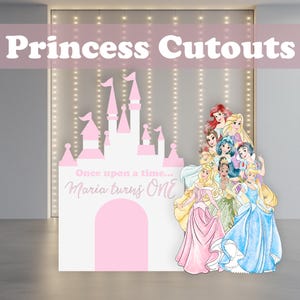 May include: A pink and white princess-themed cutout with the text "Princess Cutouts." The cutout features a castle, the phrase "Once upon a time... Maria turns ONE," and illustrations of several princesses. The background has string lights.