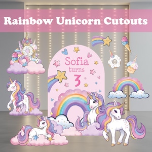 May include: Rainbow Unicorn Cutouts. A collection of colourful unicorn-themed decorations. The set includes unicorn figures, rainbows, clouds, stars, and treats like donuts and ice cream cones. The text "Sofia turns 3" is also visible.