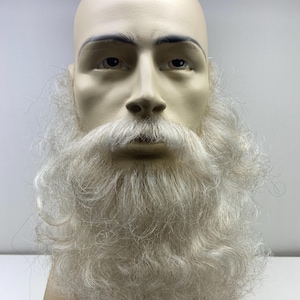 May include: A white, long, curly beard and mustache on a mannequin head. The beard is thick and full, with a lot of volume.