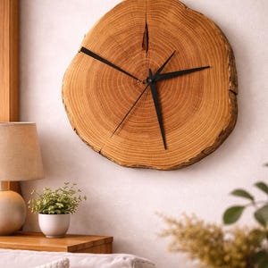 May include: A circular wooden clock with black hands, mounted on a white wall. The clock face is a cross-section of a tree trunk, displaying the natural wood grain. The clock is a decorative item in a living room setting.