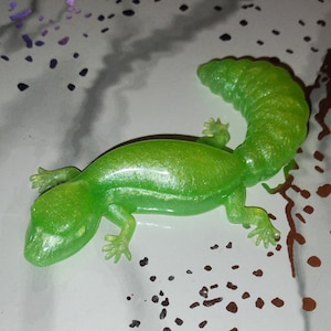 May include: A green, glittery, plastic toy lizard with a curled tail.