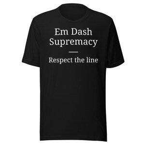 Può includere: T-shirt nero con la scritta bianca "Em Dash Supremacy" sopra "Respect the line". La maglietta è a girocollo.