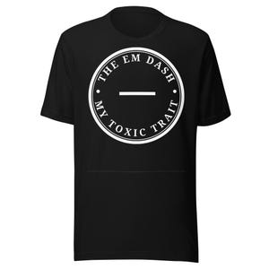 Può includere: T-shirt nero con un design circolare bianco. Il design include il testo "THE EM DASH MY TOXIC TRAIT" disposto in cerchio attorno a una linea orizzontale. La maglietta è realizzata in materiale morbido.