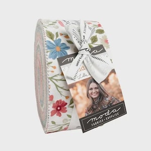 May include: Rolled fabric bundle with a floral pattern in shades of blue, red, and green on a white background. A white ribbon with a tag featuring a woman's photo and the words "moda FABRICS + SUPPLIES" is tied around the bundle.