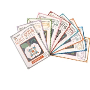 May include: A set of nine colorful quilt patterns featuring pumpkin designs. The patterns are titled "Autumn Quilt Seeds" and each pattern is numbered. The patterns are printed on paper and have a vintage aesthetic.