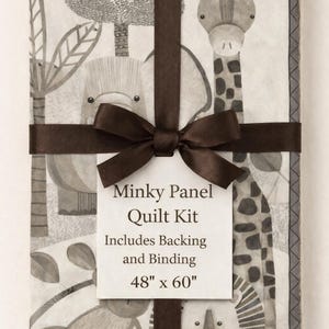 May include: A Minky Panel Quilt Kit wrapped with a brown ribbon and bow. The quilt features a safari animal design with a giraffe, lion, and elephant. The kit includes backing and binding and measures 48" x 60".