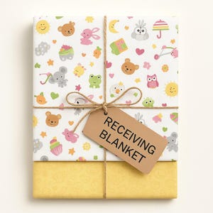 May include: A wrapped receiving blanket with a whimsical pattern of cartoon animals, cupcakes, and suns on a white background. The blanket is tied with twine and a brown tag that reads "RECEIVING BLANKET". The bottom layer is yellow.