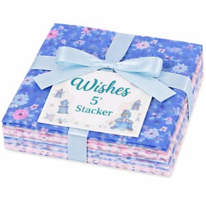 May include: A stack of floral fabric squares, tied with a light blue ribbon. The fabric features a blue background with pink and white flowers. A tag reads "Wishes 5" Stacker" with a cartoon illustration.