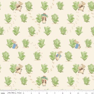 May include: A cream-colored fabric featuring a repeating pattern of brown rabbits and green lettuce heads. The rabbits are depicted in various poses, some wearing blue jackets. Small brown paw prints are scattered across the 12-inch scale.