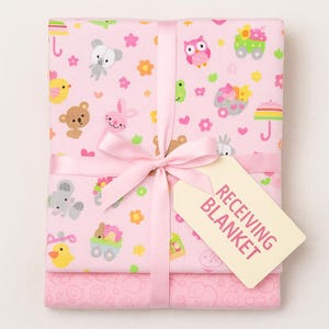 May include: A pink receiving blanket set tied with a pink ribbon. The blankets feature a repeating pattern of cartoon animals, flowers, and umbrellas. A tag reads "RECEIVING BLANKET".