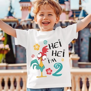 May include: A white short-sleeved t-shirt featuring a graphic of a cartoon rooster with large eyes, a yellow hibiscus flower, a red hibiscus flower, and the text "HEI HEI I'M 2" in black lettering with a large teal number two.