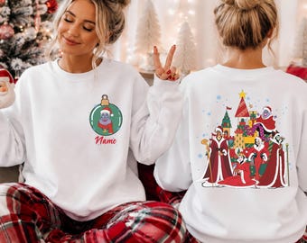 Puede incluir: Una sudadera blanca de cuello redondo con un gráfico de adorno navideño verde en el pecho izquierdo con el texto Name, y un gran estampado en la espalda que representa a varios villanos animados vestidos con ropa de Santa roja entre regalos.