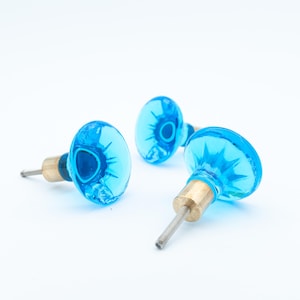 Könnte beinhalten: Eine weiße Keramik-Tasse mit schwarzem Henkel und dem Text "But First, Coffee" in fetter, schwarzer Schrift. Die Tasse steht vor einem verschwommenen Hintergrund, der eine gemütliche Umgebung suggeriert.