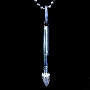 May include: A silver paintbrush pendant necklace with a silver chain. The paintbrush is detailed with a textured brush head.