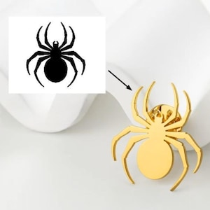 Puede incluir: Un broche de araña dorado con un diseño detallado. El broche presenta una araña con un cuerpo redondeado y ocho patas. Una ilustración de araña en blanco y negro se muestra junto al broche. El broche está sobre una superficie blanca.