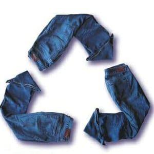 May include: Three pairs of blue denim jeans arranged in a triangular recycling symbol shape. Each pair of jeans is folded to form one of the three segments of the loop, showcasing the dark blue fabric, waistbands, and back pockets of the denim.