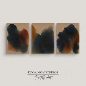 Puede incluir: Tres impresiones de arte mural cuadradas con diseños abstractos de acuarela. Cada impresión presenta una mezcla única de tonos azul oscuro, óxido y beige sobre un fondo texturizado. Las impresiones son de Kookimon Studios.