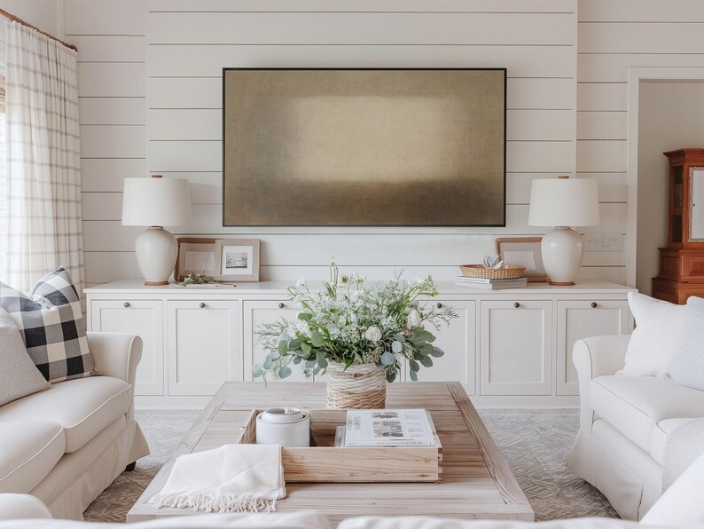 Bright neutral transitional living room with white cabinets, soft furnishings, and layered décor highlighting a Samsung Frame TV on a shiplap wall. The Frame TV features soft beige and earth-toned layers with a diffused central form and subtle textured surface. Designed for Frame TV, this neutral artwork creates a calm, gallery-style presence on a television, blending naturally into modern, Japandi, and minimalist interiors.