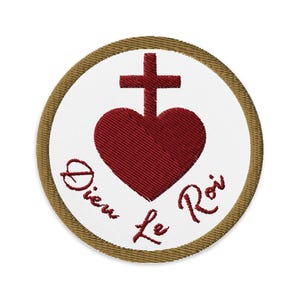 Pode incluir: Patch bordado com um design de coração e cruz vermelhos sobre fundo branco, com as palavras "Dieu le Roi" em escrita vermelha. O patch tem uma borda marrom.