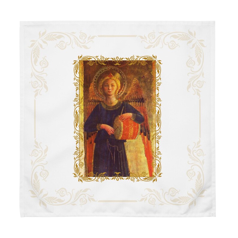 以下が含まれることがあります： 太鼓を持つ天使の額装された画像が特徴の白い正方形の布。天使は金色の光輪を持ち、青いローブを着ています。画像は金色のフレームで囲まれ、装飾的な花のボーダーが付いています。