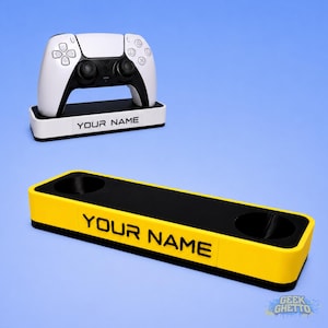 May include: A white and black gaming controller on a white base with the text "YOUR NAME". Below is a yellow and black charging station with the text "YOUR NAME". The background is light blue.