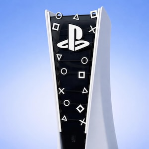 Op de afbeelding: Een witte en zwarte PlayStation 5 console. De console heeft een zwart middengedeelte met witte symbolen en het PlayStation-logo. De console heeft een gebogen ontwerp en staat tegen een blauwe achtergrond.