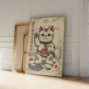 Könnte beinhalten: Eine Vintage-Illustration eines weißen Maneki-Neko, oder japanischen Glückskatze, mit einer goldenen Münze in der Pfote. Die Katze sitzt auf einer Welle mit einem roten Kreis dahinter. Die Illustration ist von einem hellbraunen Rahmen umgeben.
