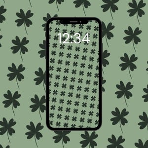 May include: A black smartphone displays a green clover pattern wallpaper with the time 12:34. The background features a repeating pattern of dark green four-leaf clovers on a light green backdrop.