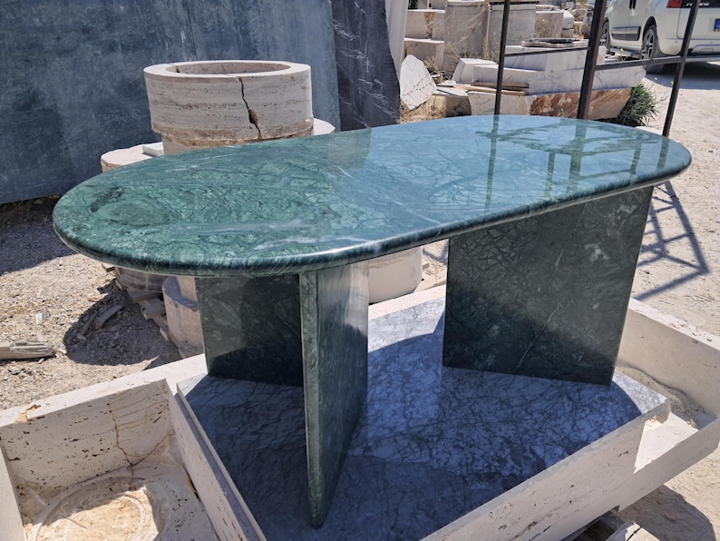 Puede incluir: Mesa de m&aacute;rmol verde con tapa rectangular redondeada y dos patas de soporte. La mesa tiene una superficie pulida y un patr&oacute;n de vetas natural. La mesa mide aproximadamente 152 cm de largo y 76 cm de ancho.
